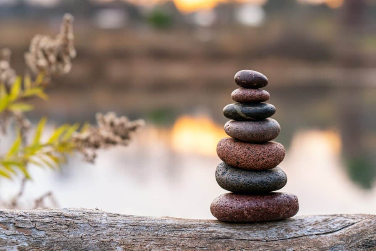 Zen stones stacked up in the foreground of a placid lake