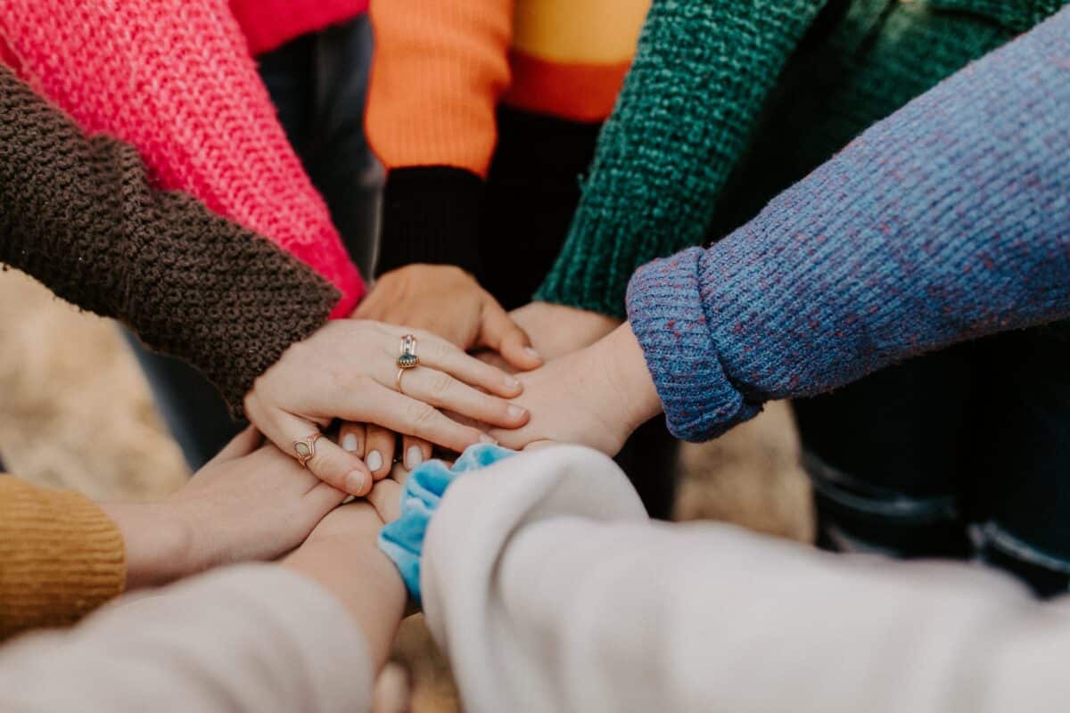 Multiple parent volunteers hands piling into one stack in a teamwork fashion