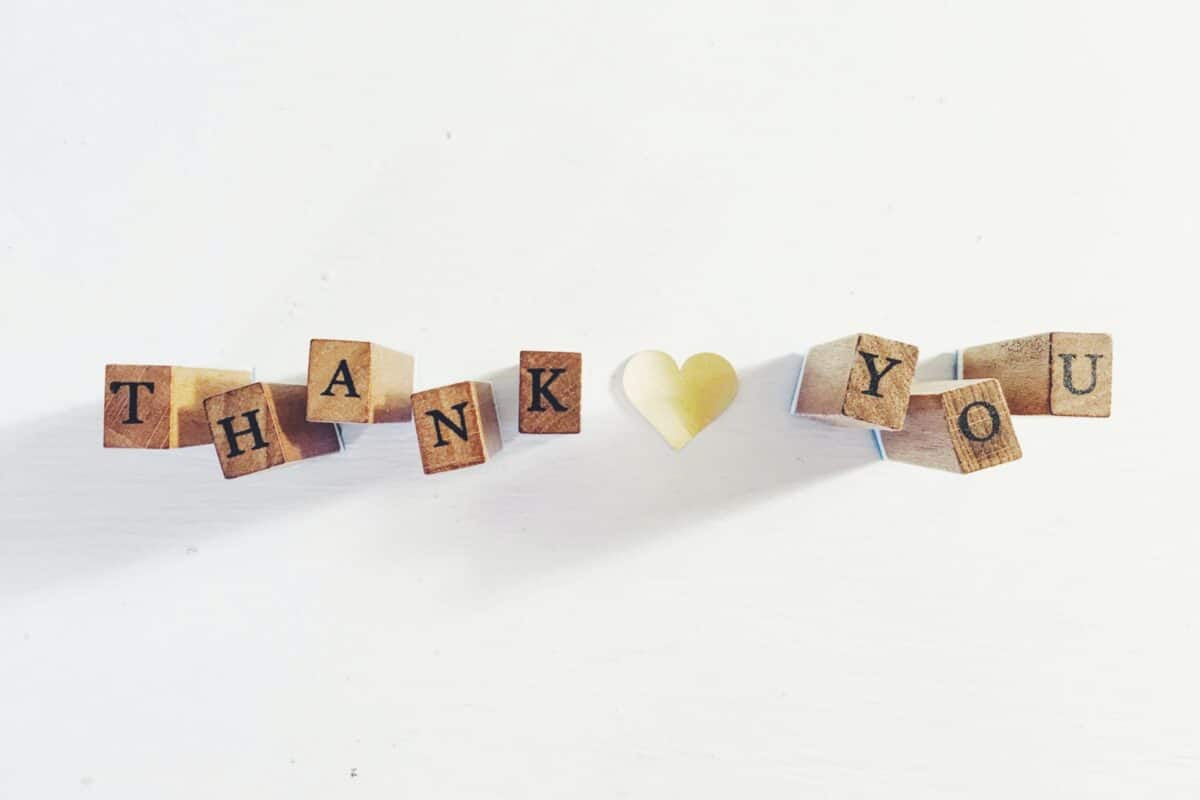 scrabble pieces spelling out "thank you" with a yellow heart in the middle